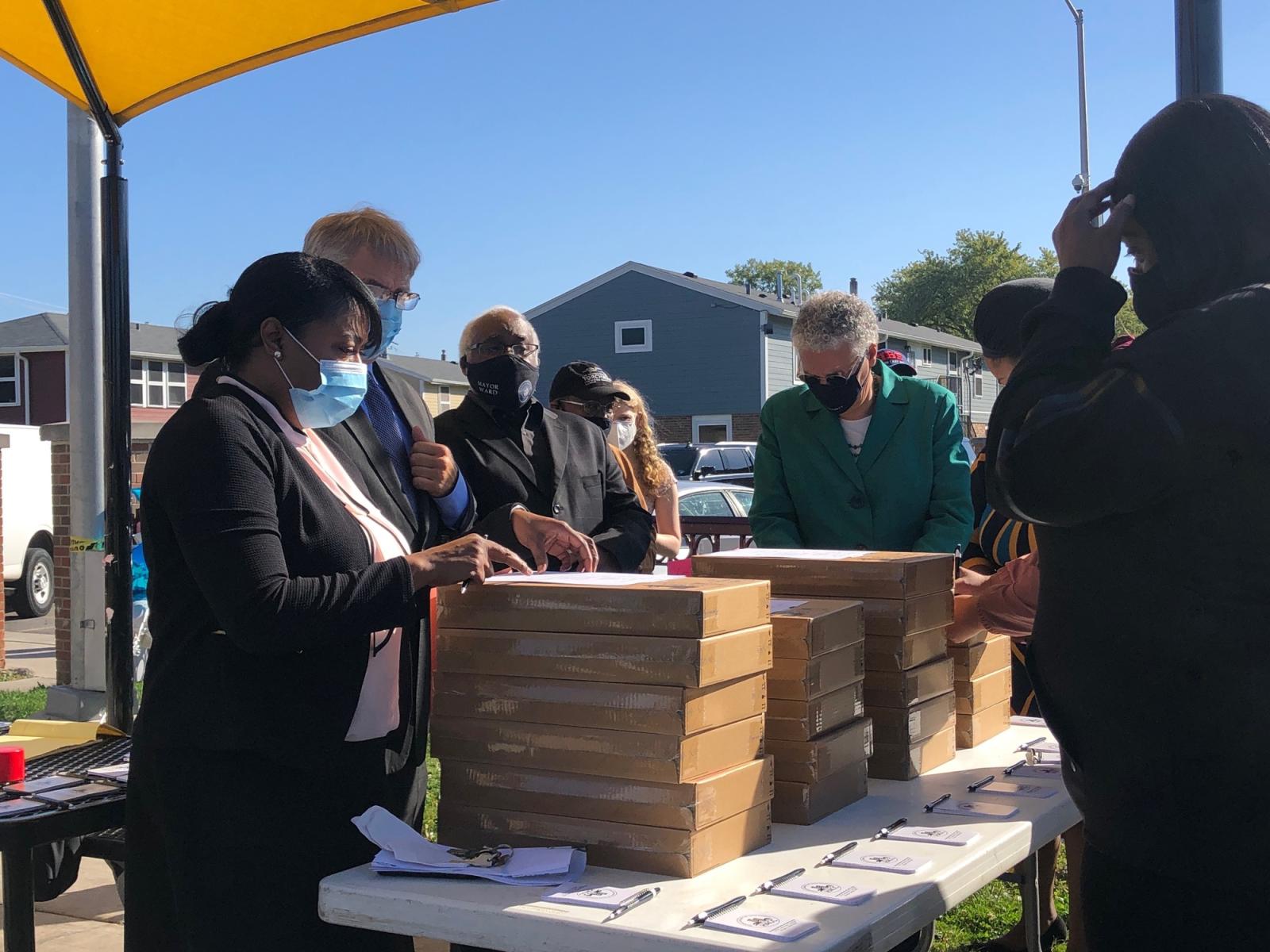 cook county board president and housing authority of cook county executive director distributing boxed laptops outdoors
